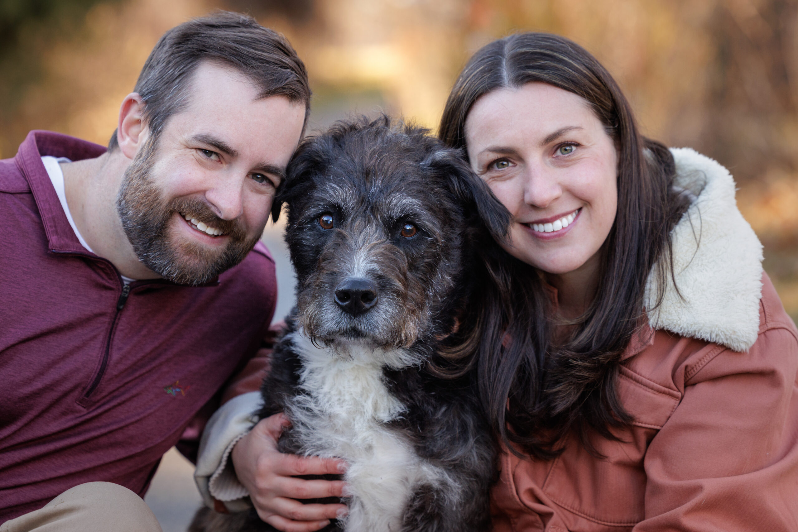 couple snuggling their dog on his end of life session at their home